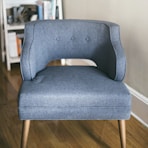 person taking photo of grey padded chair inside room