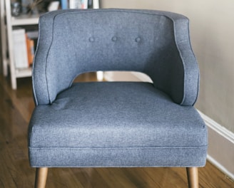 person taking photo of grey padded chair inside room