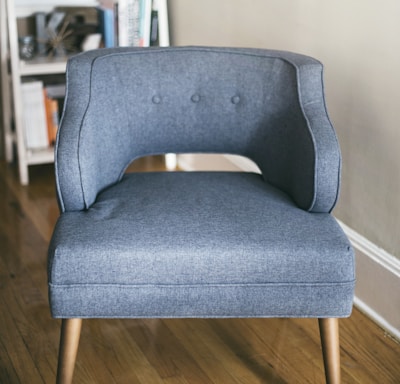 person taking photo of grey padded chair inside room