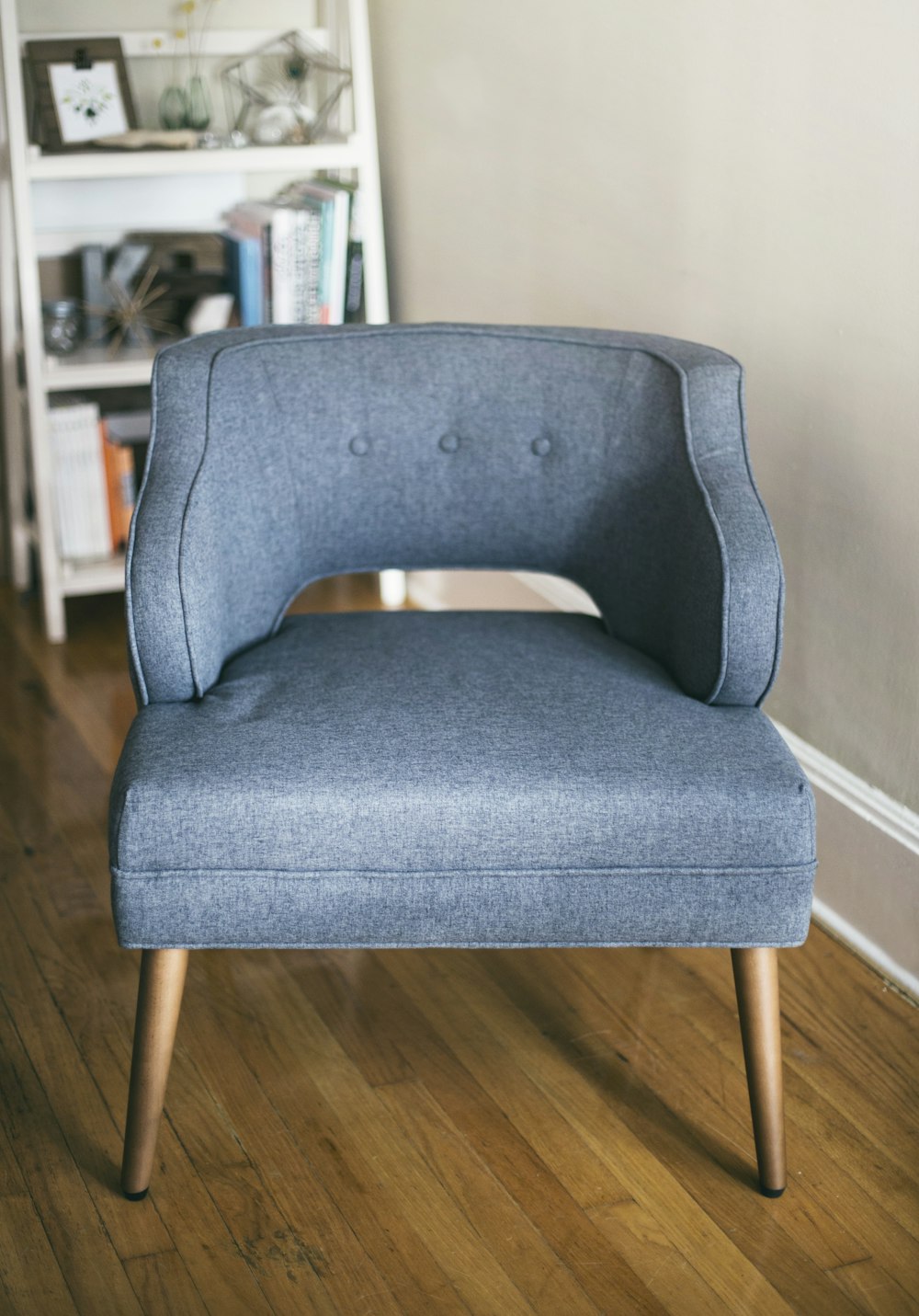 person taking photo of grey padded chair inside room