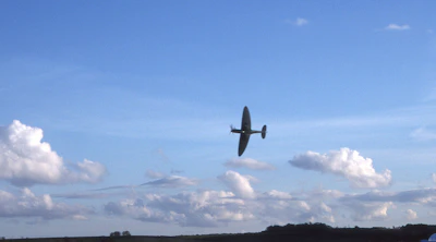 Photo of a vintage airplane soaring against a clear blue sky near Santa Fe mountains.