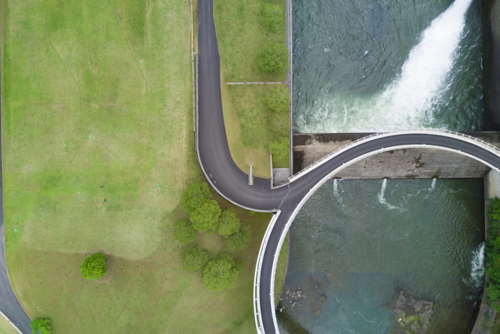 Estrada preta perto da barragem e árvores durante o dia