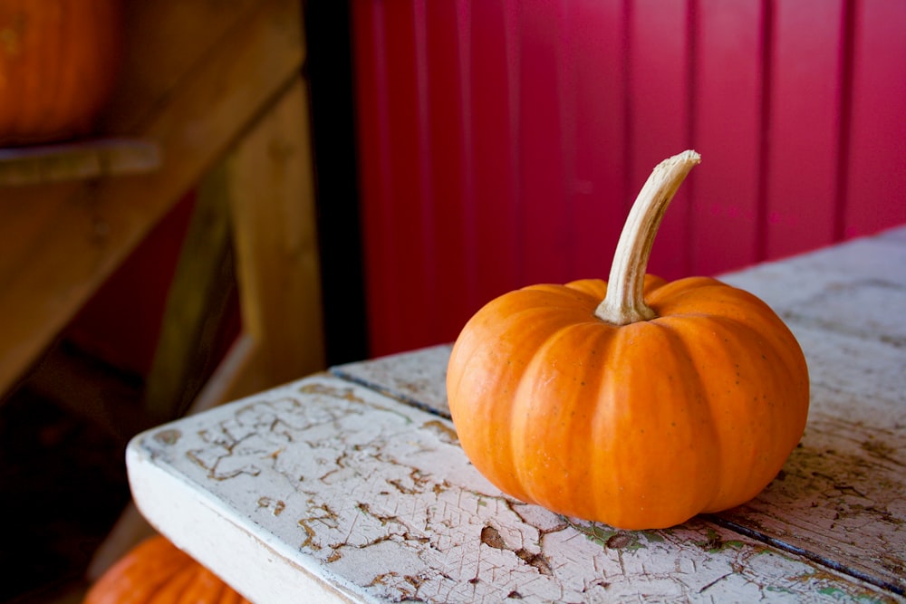 calabaza naranja sobre mesa blanca en habitación rosa