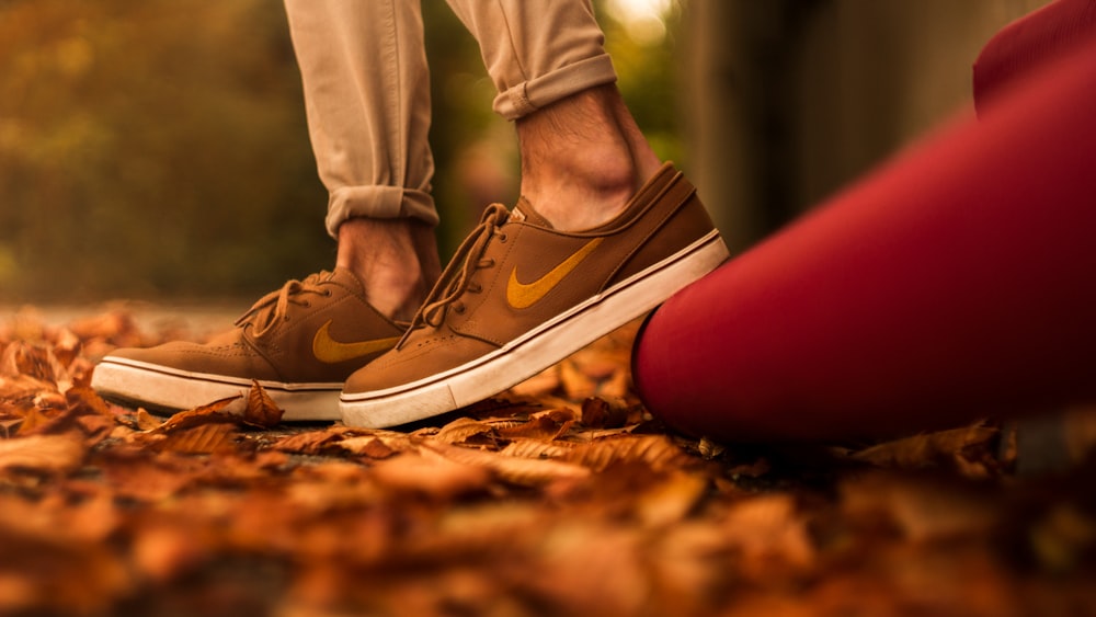 low-angle photo of person wearing pair of brown Nike sneakers
