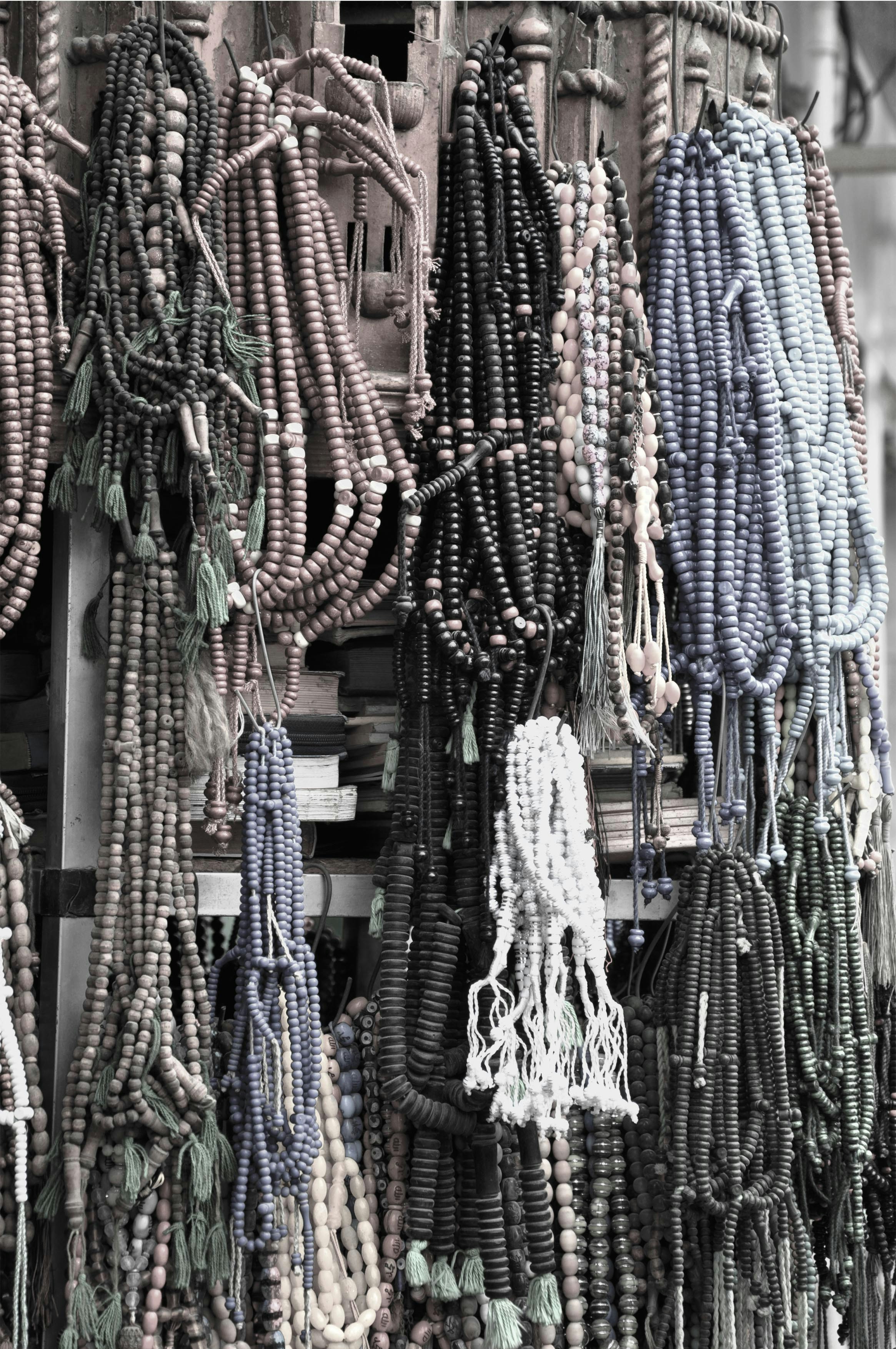 Diverse collection of prayer beads spread on white surface, various materials and colors