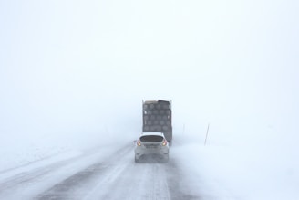 white car behind a truck on snowy road