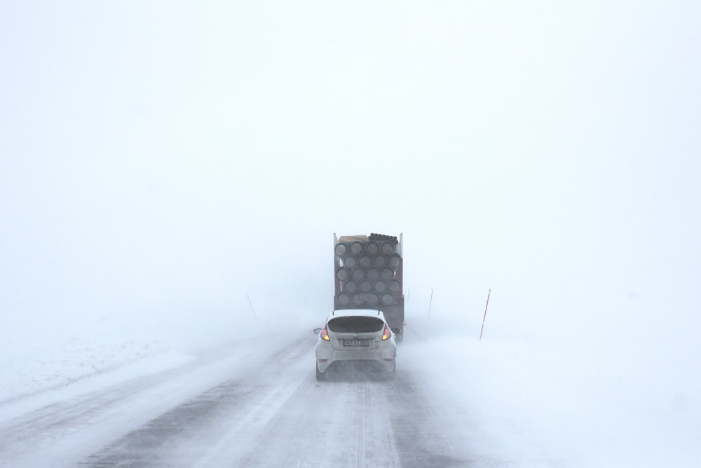 white car behind a truck on snowy road