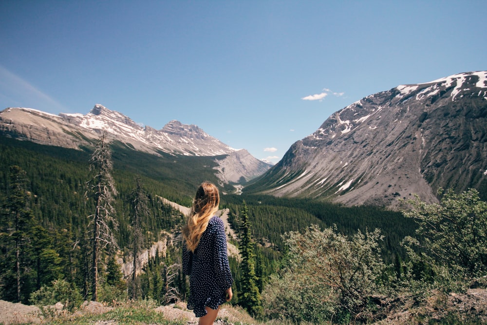 woman standing in front of mountain range under clear blue sky during daytime