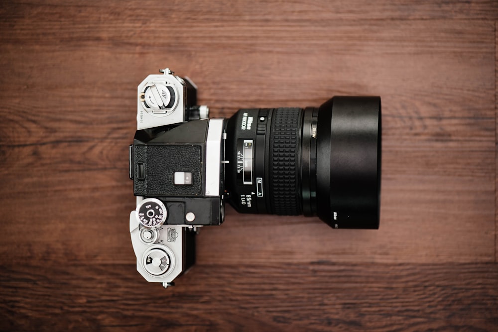 black and gray DSLR camera on brown surface