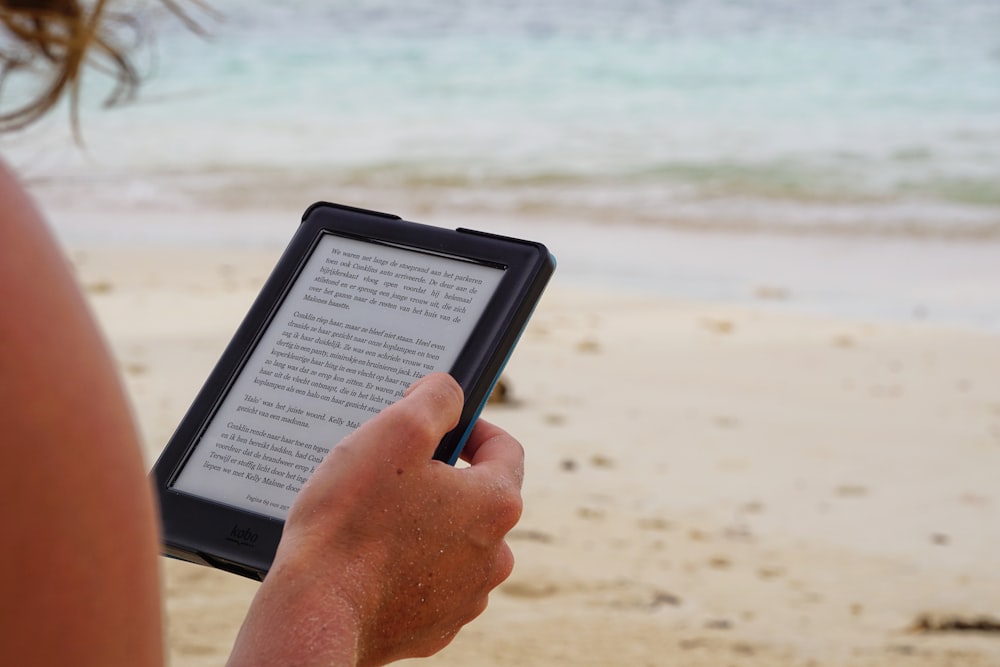 person holding black tablet computer during daytime