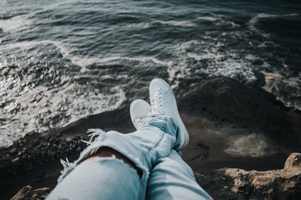 person sitting on mountain cliff across body of water