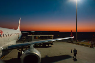 Airplane being refueled at a modern service station at sunset.