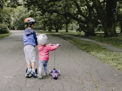 two toddler's walking on road near green tree