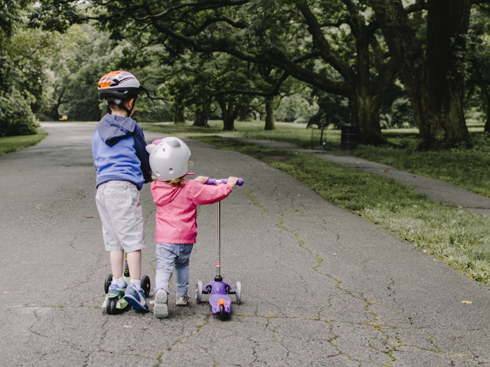 two toddler's walking on road near green tree