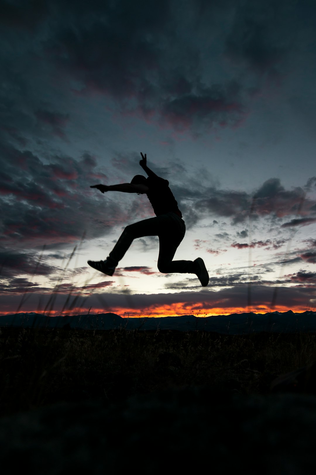 man leaping above ground under cloudy skies golden hour photography