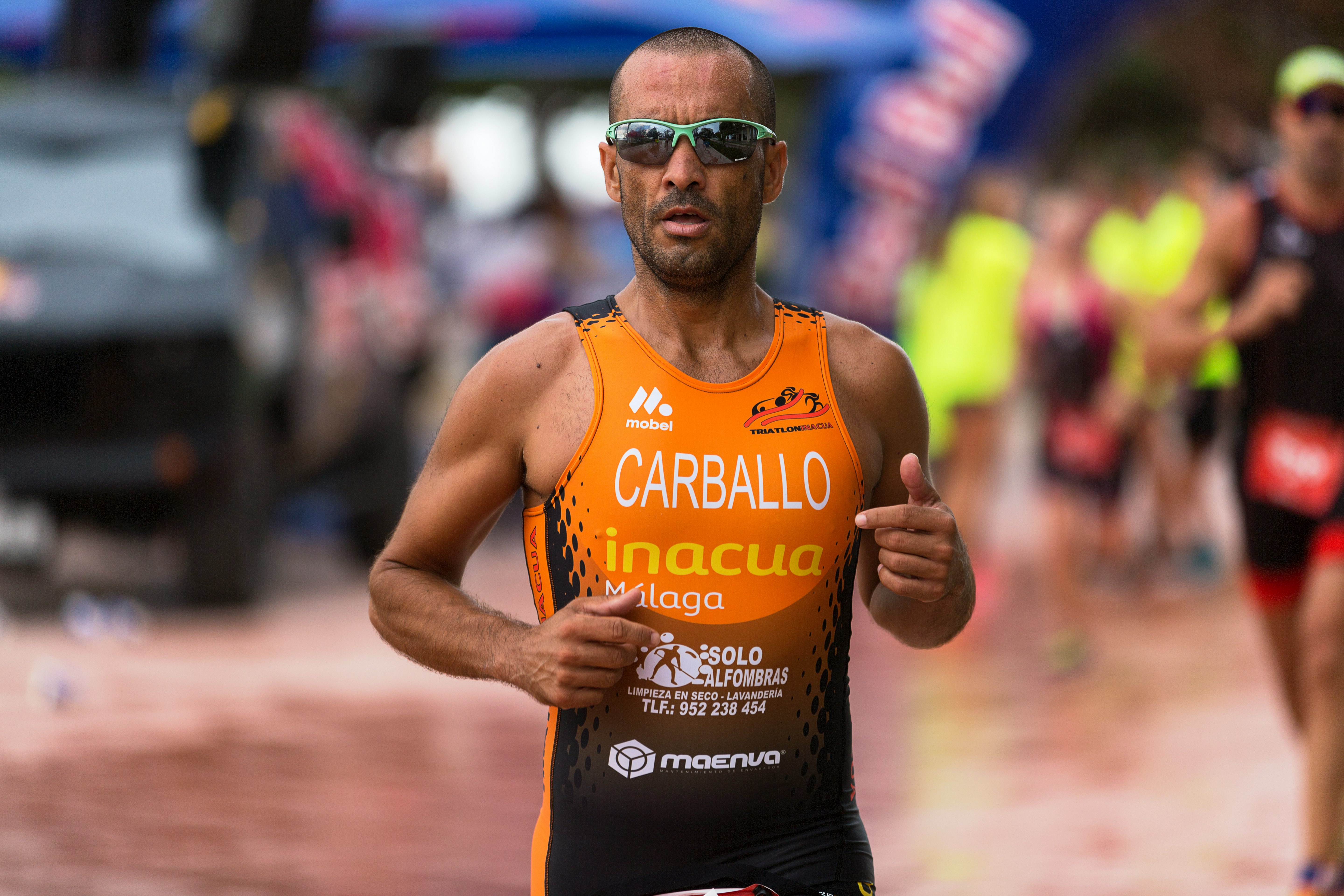 man wearing orange tank top and gray framed sport sunglasses