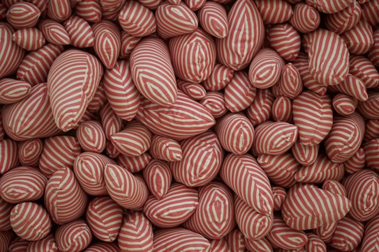 A large assembly of soft, pillow-like objects densely packed together. Each object is covered in fabric with red and white stripes, creating a visually dynamic pattern.