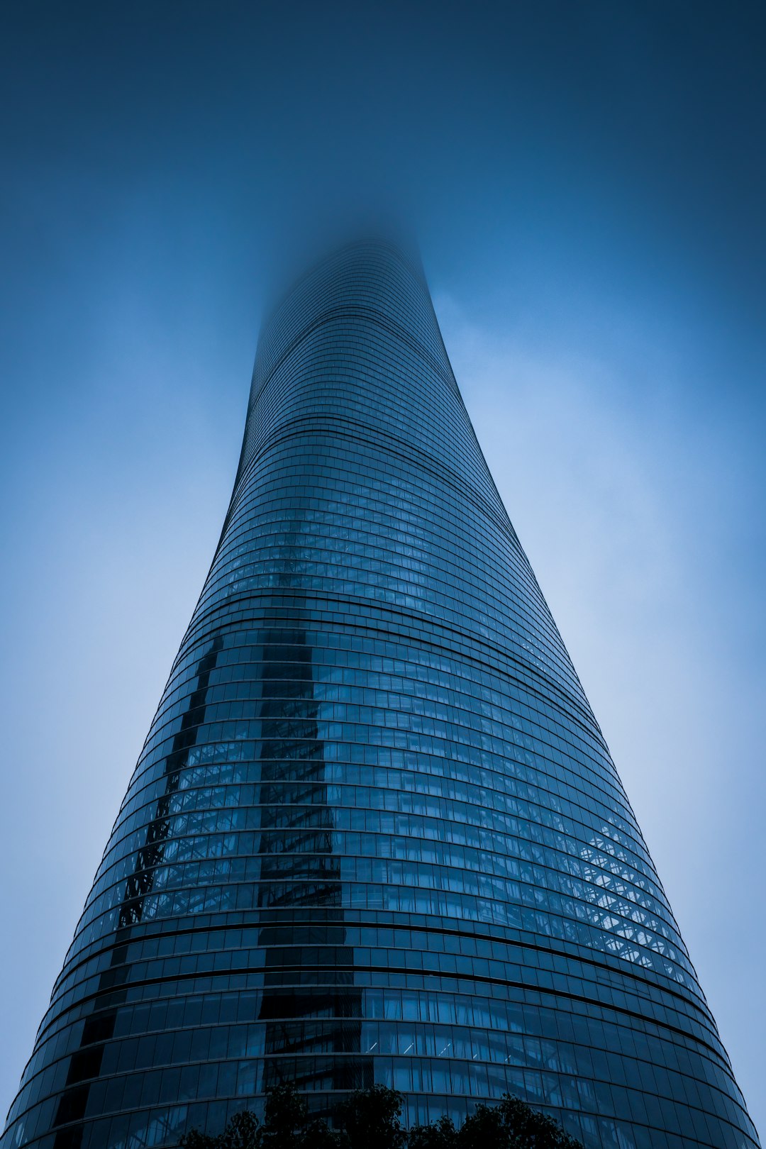 low angle photography of gray curtain wall building covered with fog