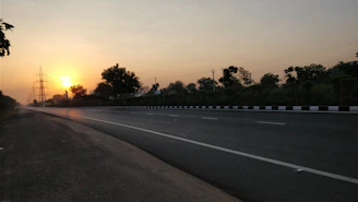 A freshly paved highway stretching through a vibrant landscape at sunrise.