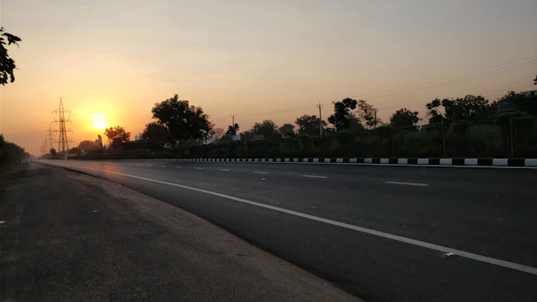 A freshly paved highway stretching through a vibrant landscape at sunrise.