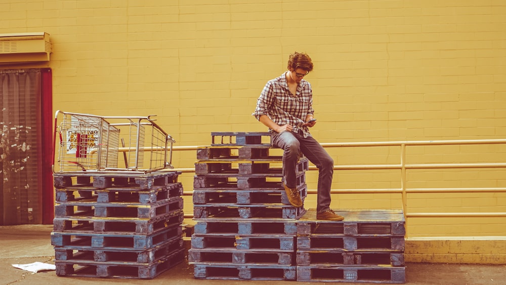 man sitting on top of pallets stack