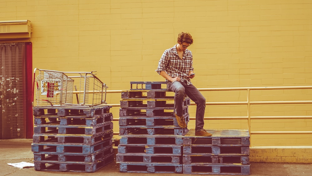 homme assis sur le dessus de la pile de palettes