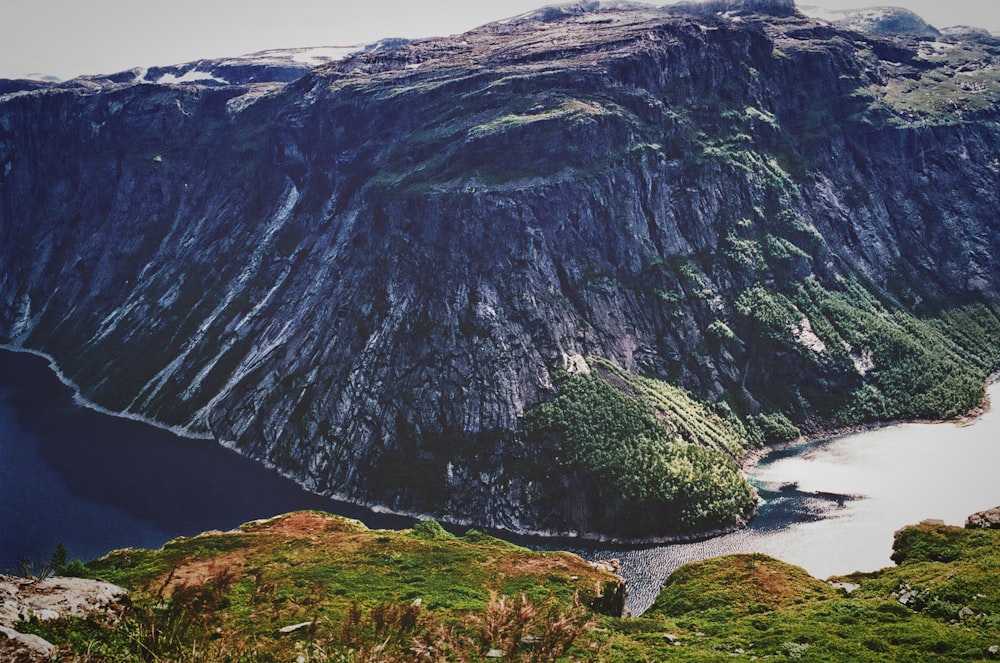 aerial photography of gray rock mountain surrounded by body of water at daytime