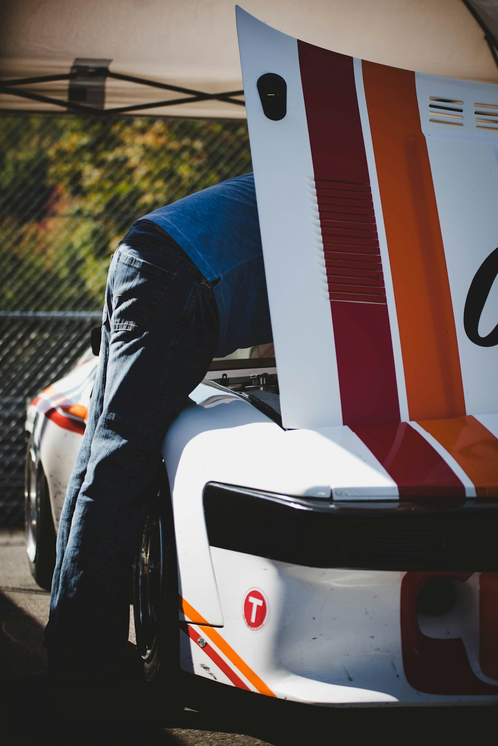 man fixing white, red, and orange vehicle engine during daytime