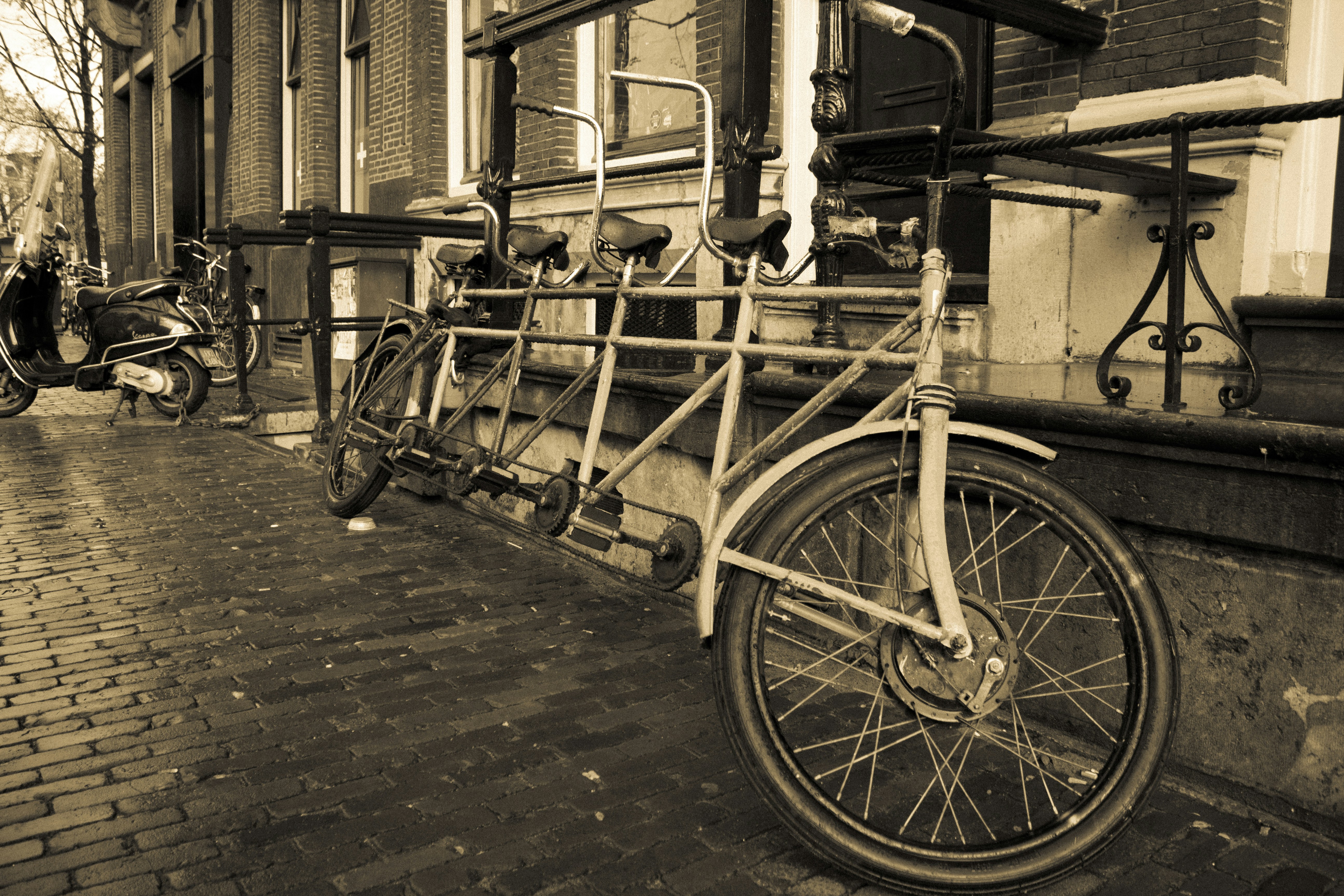 Vintage steam-powered vehicle on cobblestone road, sepia-toned atmospheric scene with heavy shadows and dark industrial background