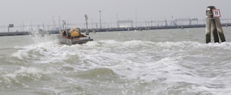 A small boat navigating through choppy waters with visible waves and splashes, moving towards a distant industrial background with structures and poles. On the right is a marker or buoy labeled with the number 11.
