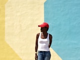 woman wearing white tank top standing next to beige and blue painted wall during daytime