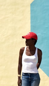 woman wearing white tank top standing next to beige and blue painted wall during daytime