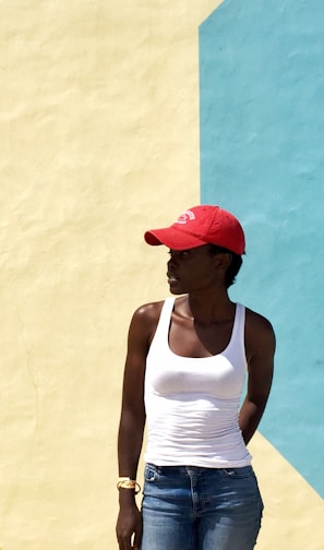 woman wearing white tank top standing next to beige and blue painted wall during daytime