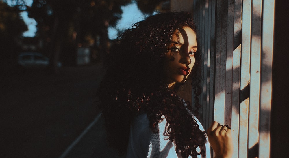 curly-haired girl leaning on steel fence outdoors