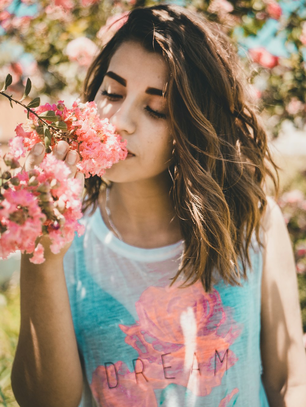 mujer oliendo flores rosadas