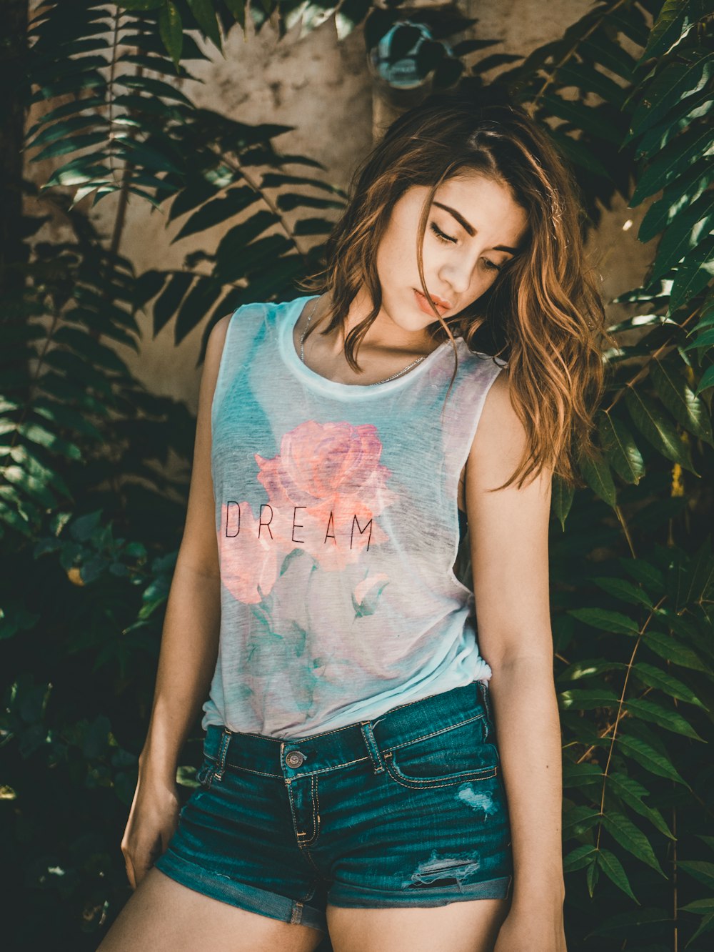 woman posing for photo beside green plants