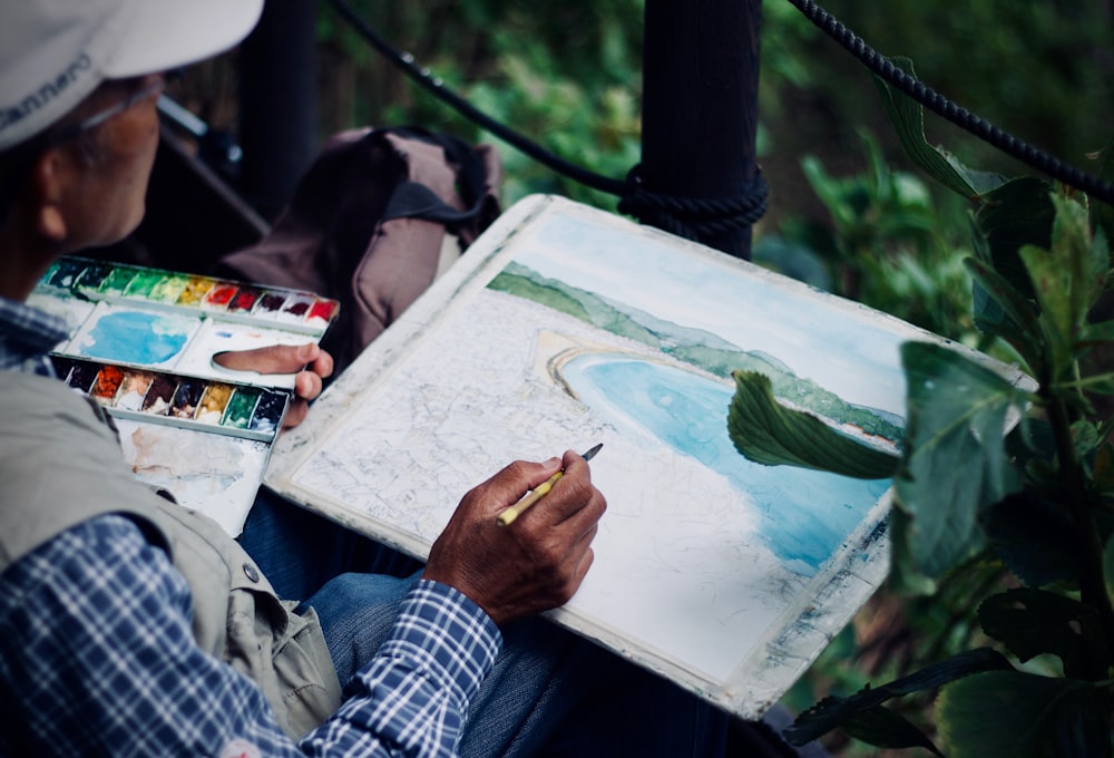 man holding brown and black pen painting seashore