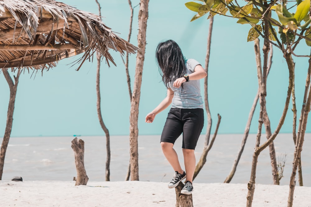 woman wearing gray shirt standing on trunk in front of sea