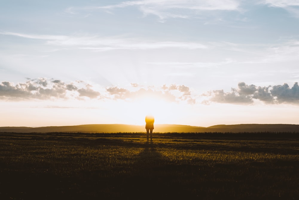 silhouette of person standing facing sun