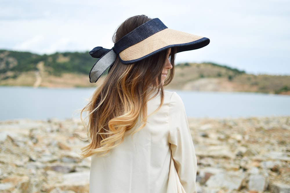 Mujer de pie cerca del lago con sombrero de visera