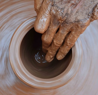 a potter's hand is spinning a pot on a potter's wheel