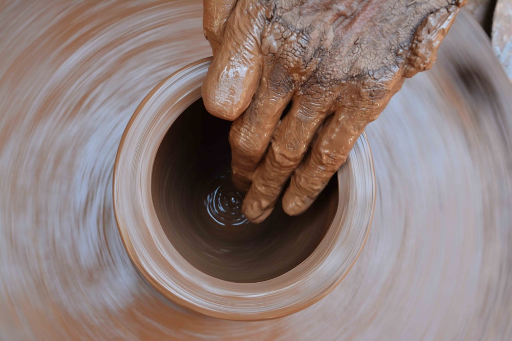 La mano di un vasaio sta facendo girare una pentola sul tornio di un vasaio