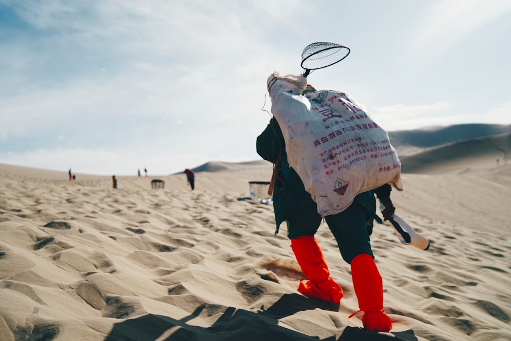 person carrying sack in the desert