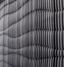 A textured wall surface featuring a series of evenly spaced vertical fins. These fins create an undulating pattern with a play of light and shadows, contributing to a rhythmic and structured appearance. The monochrome palette emphasizes the geometric design.