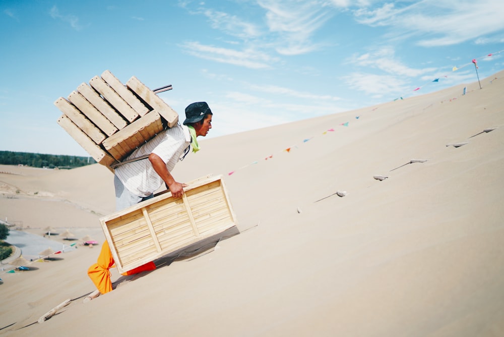 man wearing white shirt carrying brown wooden boxes