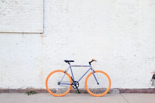 yellow and purple bicycle near white wall at daytime