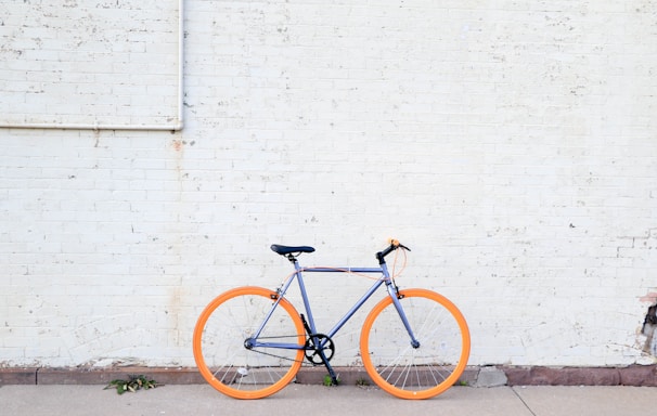 yellow and purple bicycle near white wall at daytime