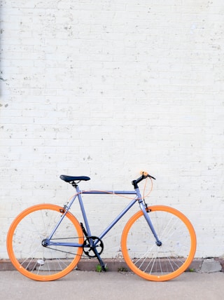 yellow and purple bicycle near white wall at daytime