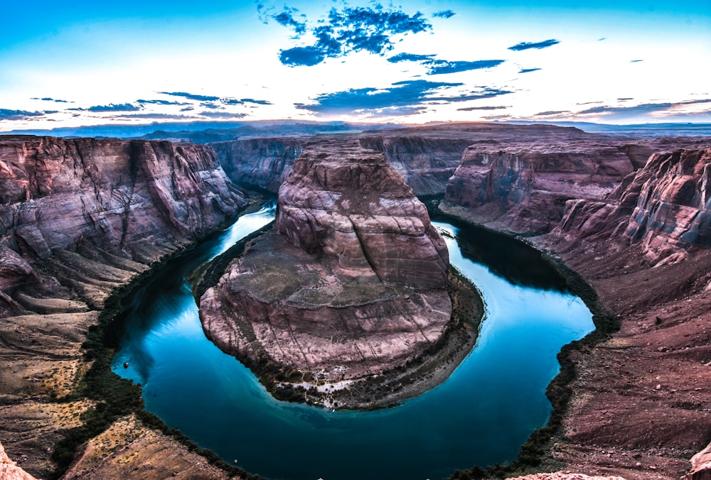 brown rock formation beside body of water under white cloudy skies at daytime