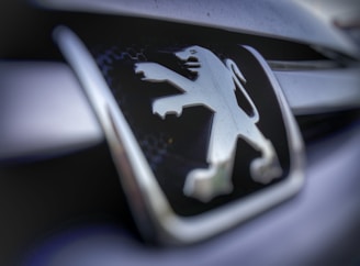 Close-up view of a metallic emblem featuring a lion, possibly on the front grille of a vehicle, with a sleek and modern design.